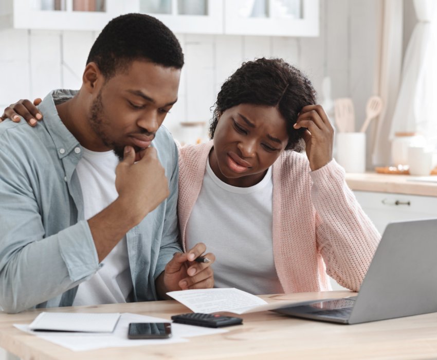 Stressed Black Couple Calculating Family Budget In Kitchen. Young African American Spouses Suffering Financial Crisis, Checking Monthly Expenses And Tax Bills Together At Home, Having Debts